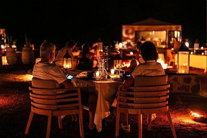 Luxury private dining setup in Agafay Desert with candles, rugs, and Moroccan decor