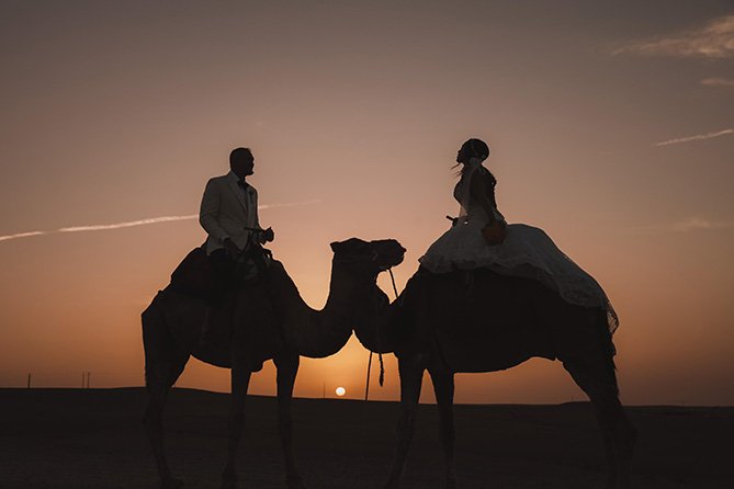 Couple enjoying romantic sunset camel ride through Agafay Desert near Marrakech